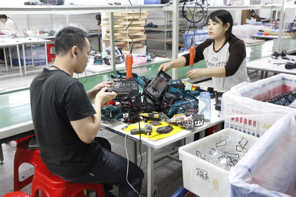 Skilled factory workers assembling RC car chassis during the production process.