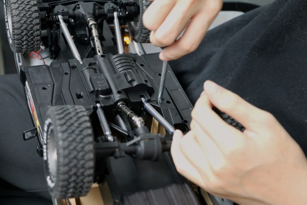 Technician inspecting and assembling an RC toy car LC80 chassis during quality control testing before shipment.