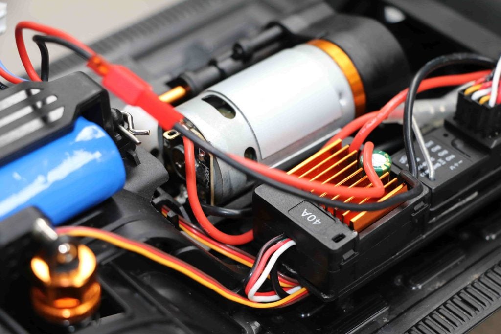 JXC 1:12 LC80 crawler front axle with servo saver, oil shock and orange steering link close-up