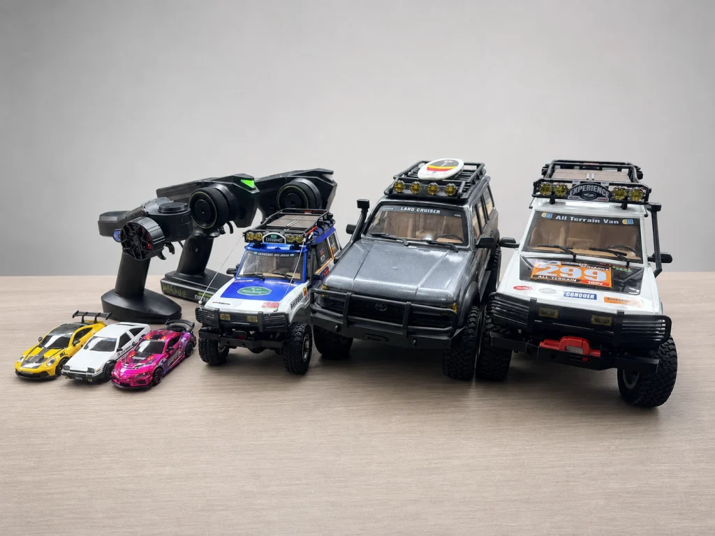 JXC RC car product lineup: 1:12 crawlers and 1:43 drift cars with remote on desk