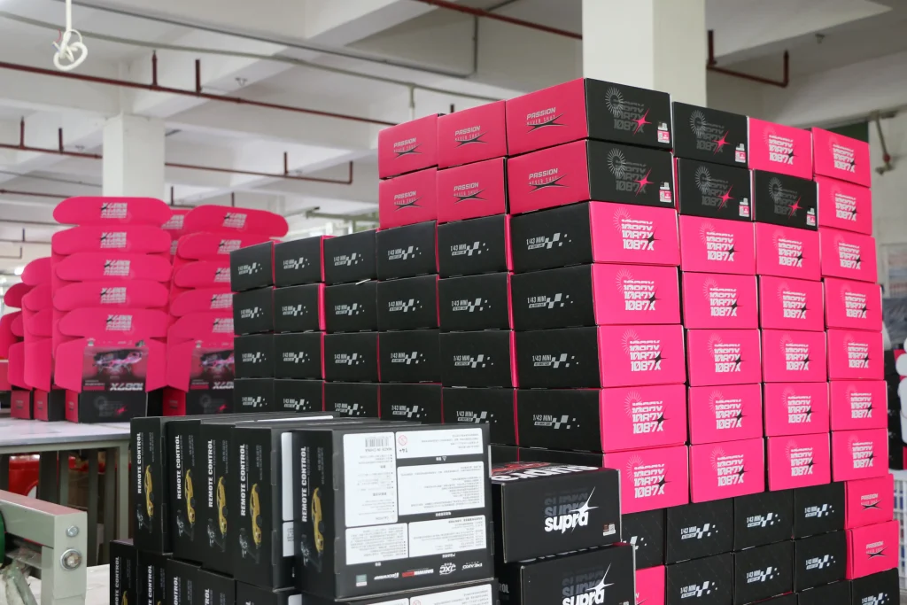 Stacked retail boxes of JXC LC80 1/12 RC crawler inside a factory warehouse for bulk supply.