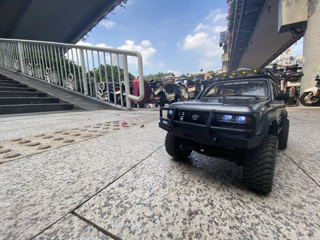 Black LC80 Land Cruiser RC crawler with LED lights on a city plaza