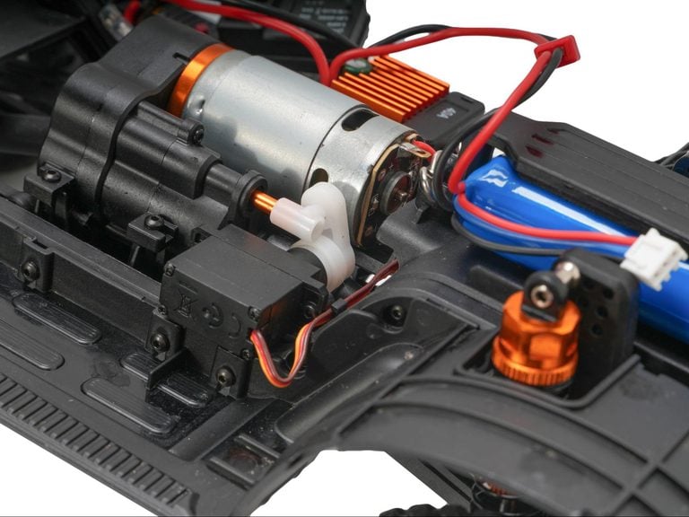 Brushed RC car motor with gearbox and wiring inside a crawler chassis.