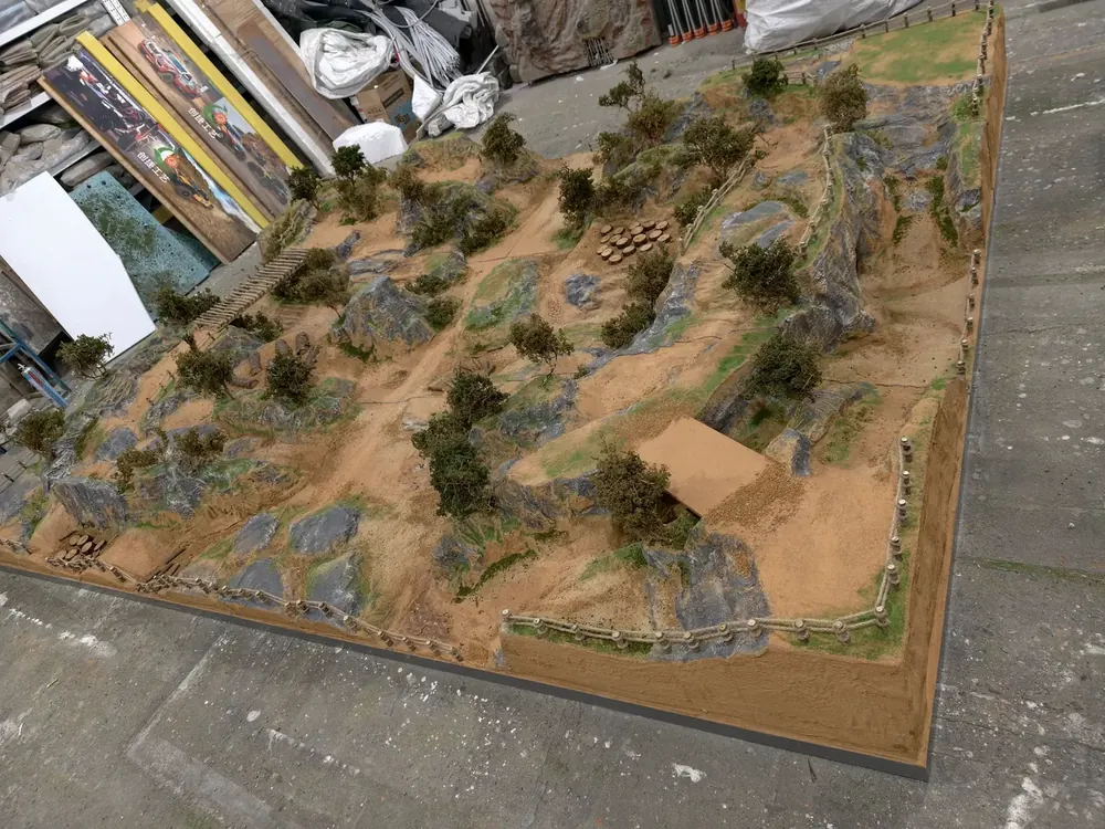 Custom indoor RC diorama track with rocky gobi terrain, photographed at the JXC Model factory before packing