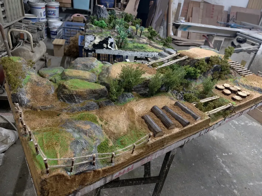 Hand-detailed rockwork, logs and fencing on an indoor RC diorama track during final assembly - JXC Model